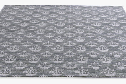 Grey rug with white tree-like motifs in a repeating pattern; flatwoven, modern rustic style for living room floors.