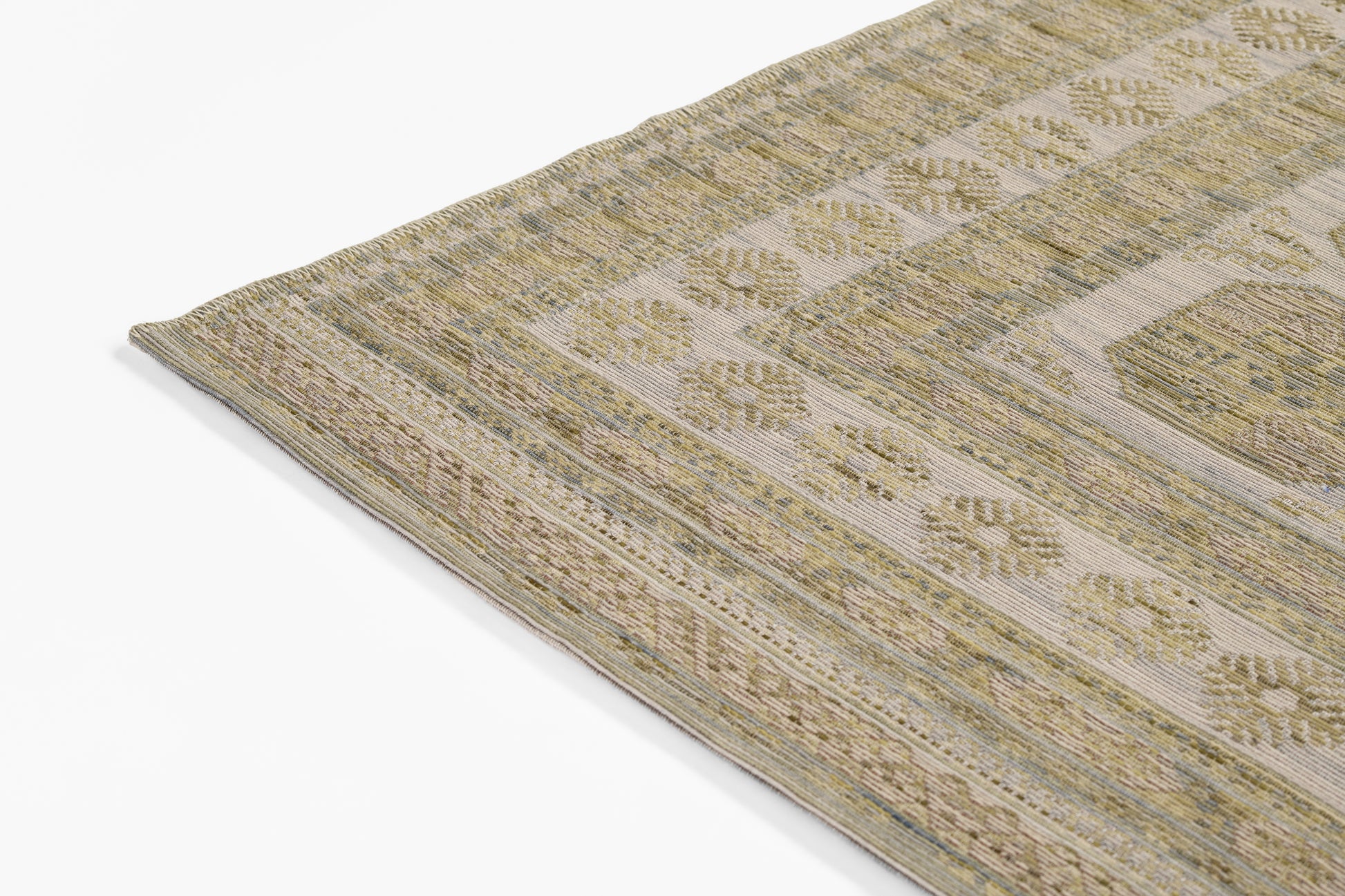 Beige-brown woven area rug with muted green floral border and geometric motifs; rectangular, textured.
