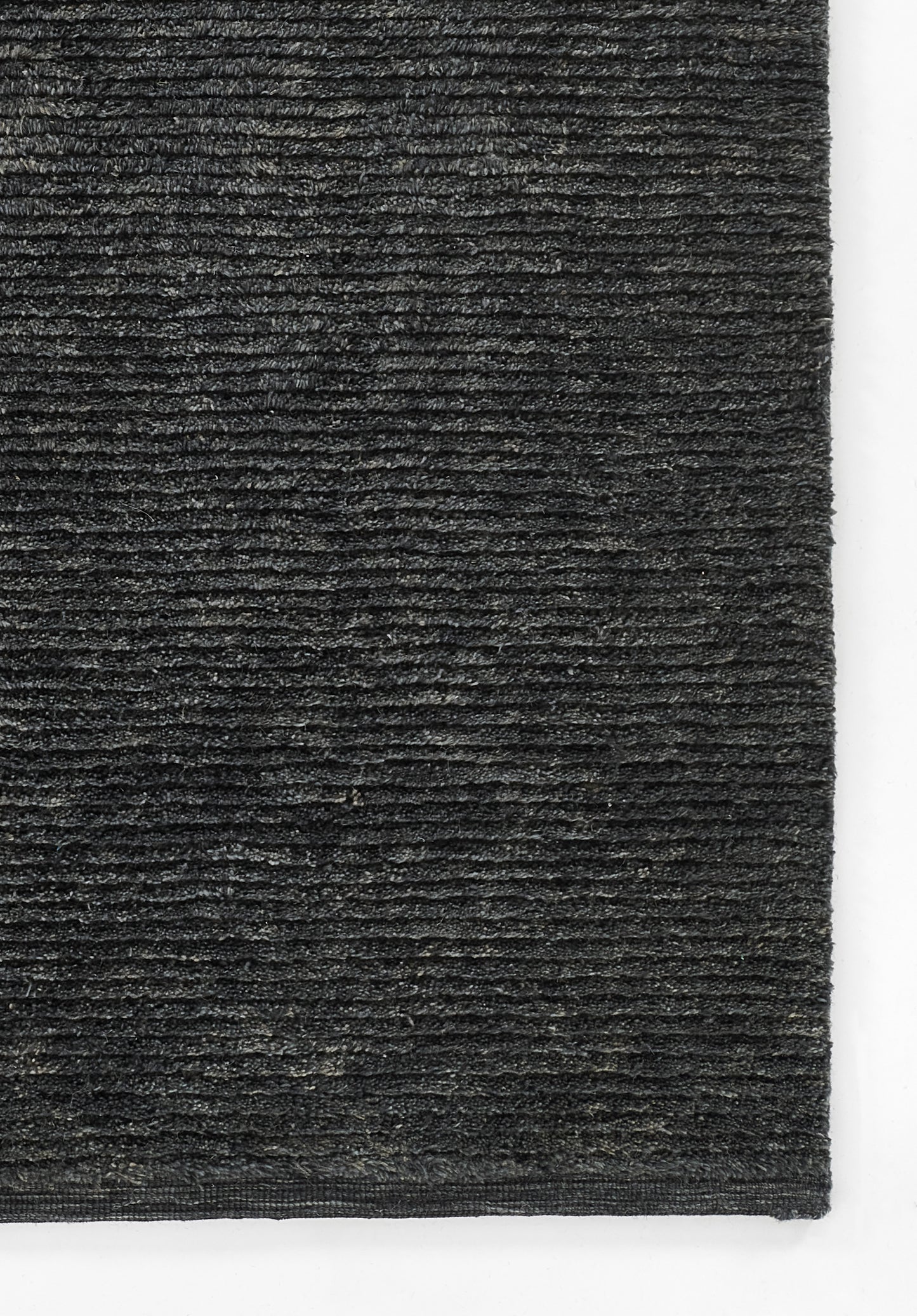 Charcoal gray loop-pile rug close-up with dense texture and horizontal ridges, rectangular floor mat.