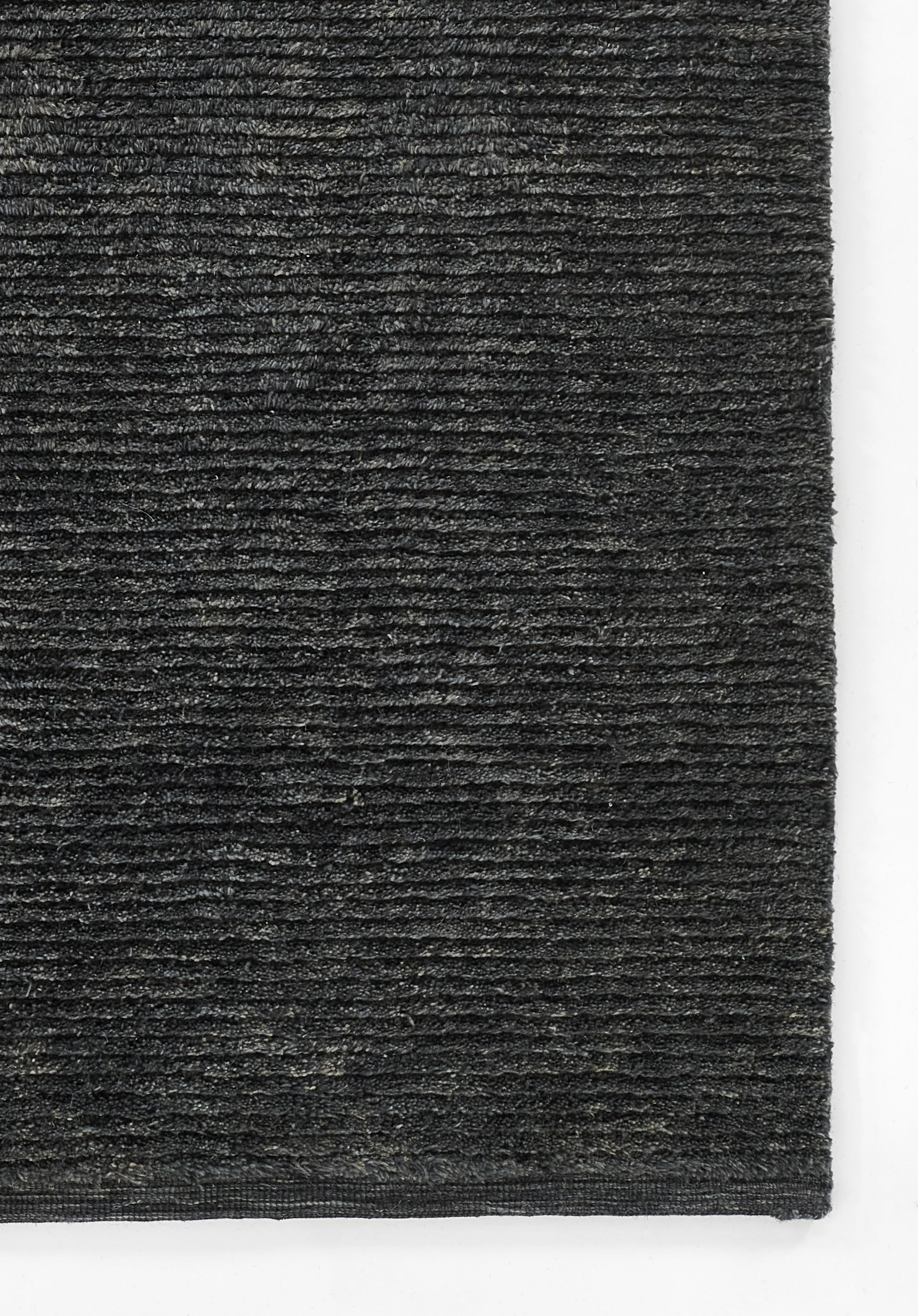 Charcoal gray loop-pile rug close-up with dense texture and horizontal ridges, rectangular floor mat.