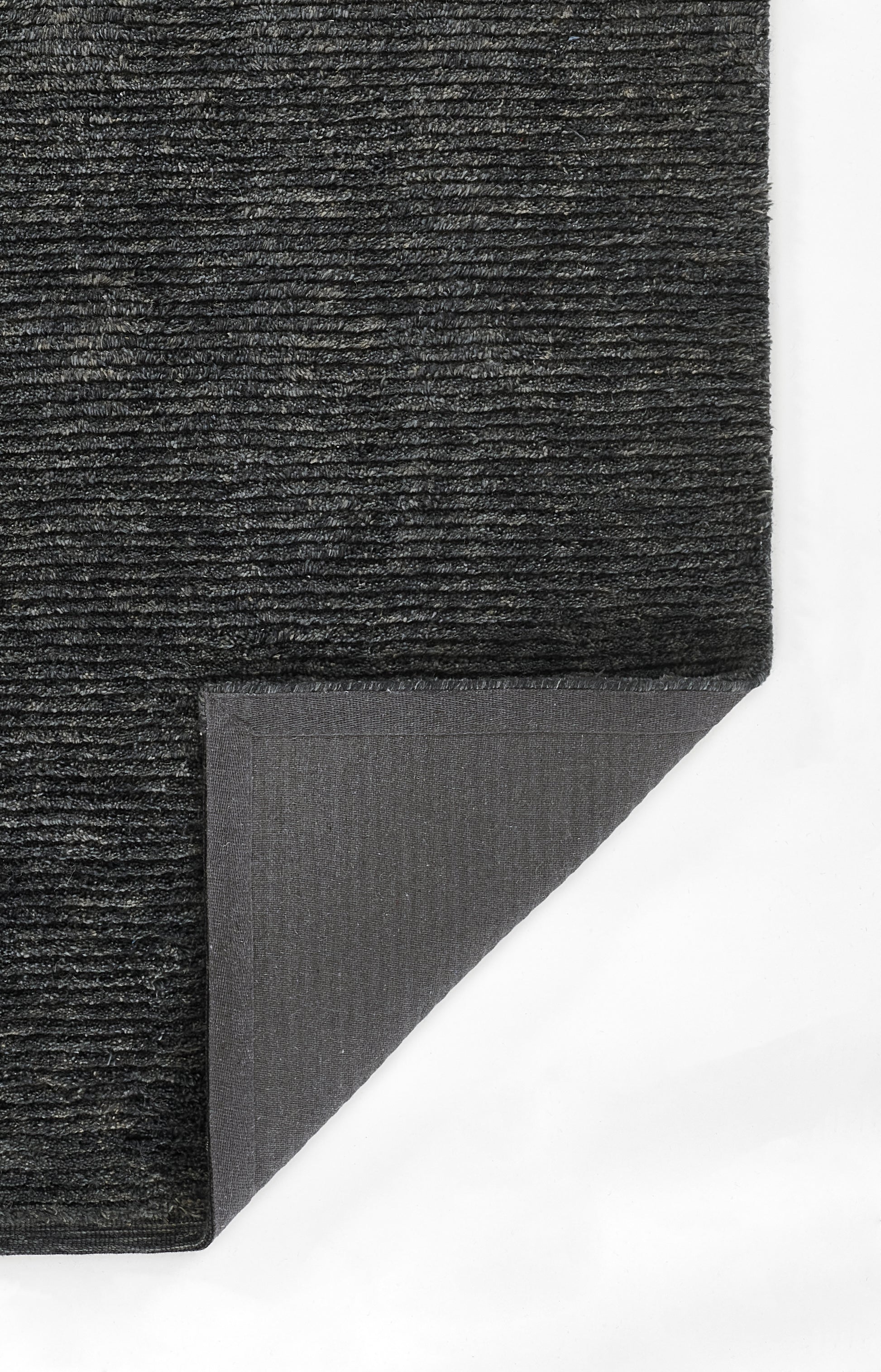 Dark charcoal rug with dense ribbed pile; corner folded to reveal gray underside.