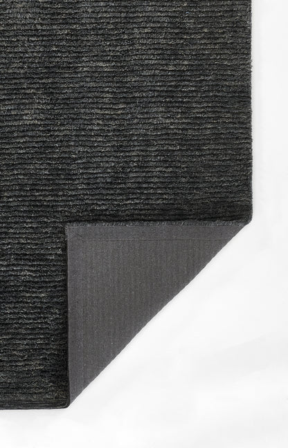 Dark charcoal rug with dense ribbed pile; corner folded to reveal gray underside.