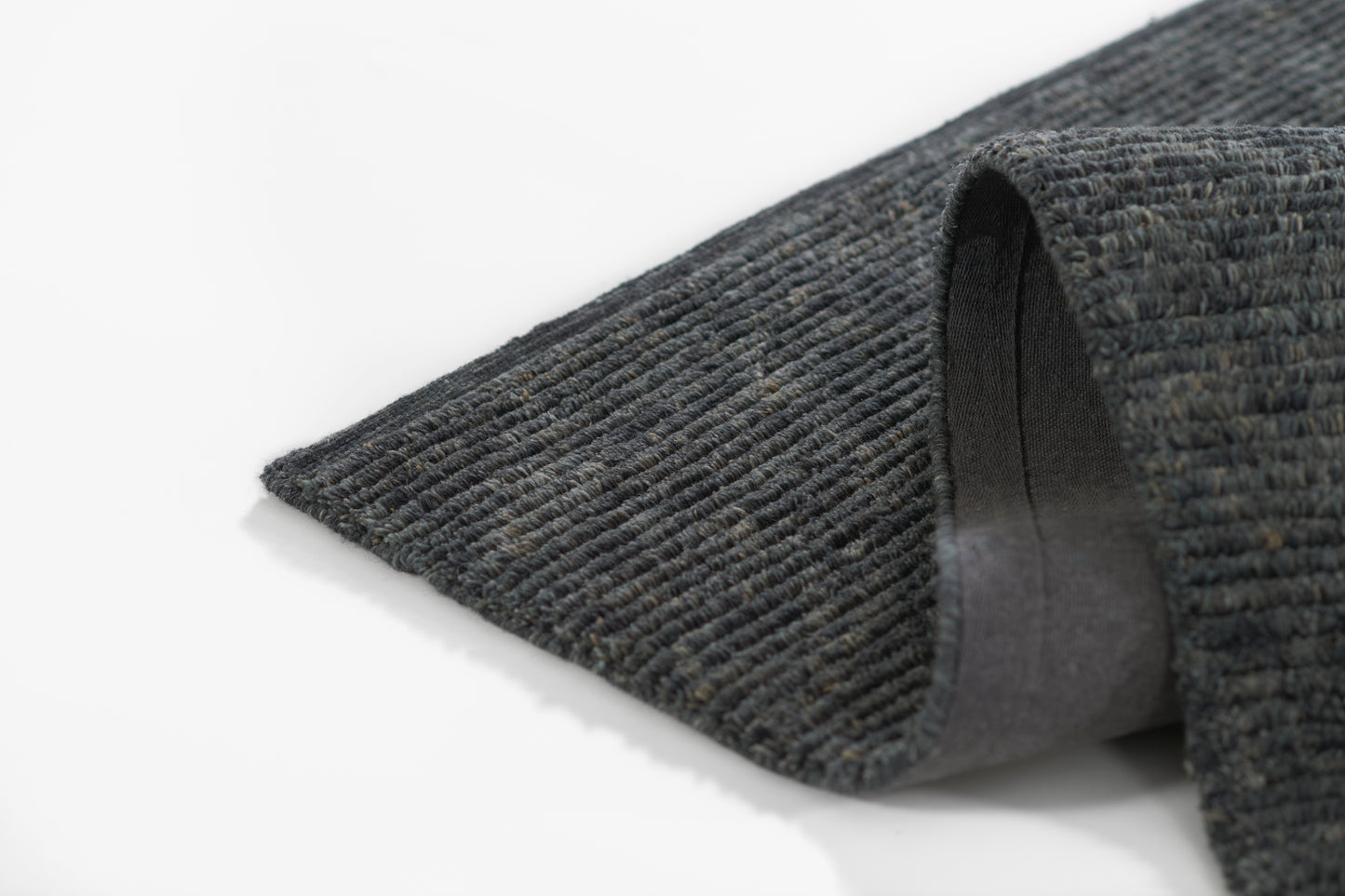 Dark grey ribbed rug with loop pile and folded edge showing soft backing.