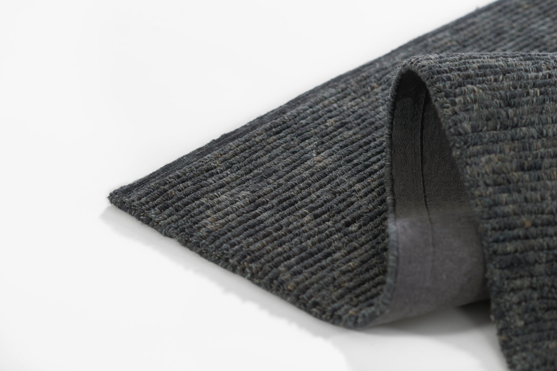 Dark grey ribbed rug with loop pile and folded edge showing soft backing.
