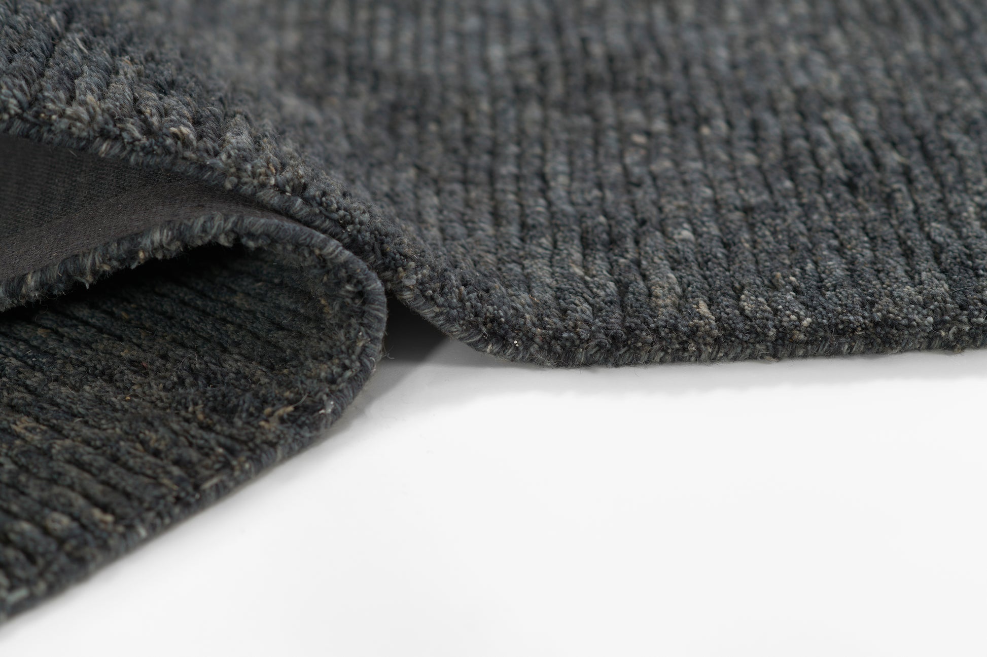 Charcoal gray ribbed rug with soft loop pile and folded edge detail.