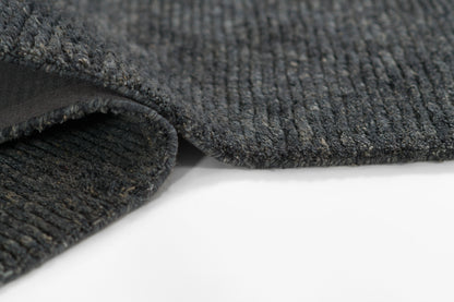 Charcoal gray ribbed rug with soft loop pile and folded edge detail.