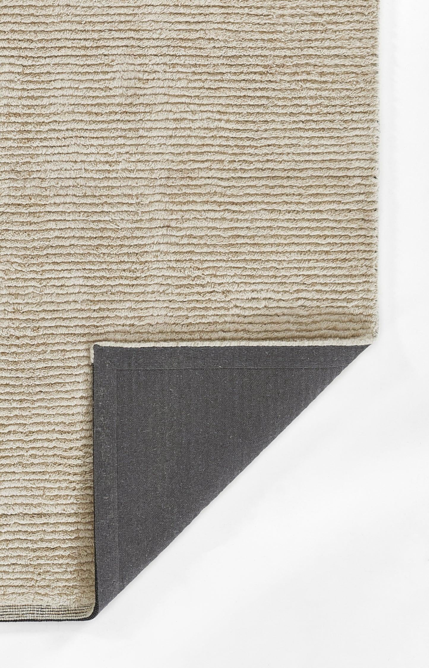 Beige textured loop-pile rug with soft surface; dark gray fabric backing visible at folded corner.