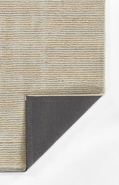 Beige textured loop-pile rug with soft surface; dark gray fabric backing visible at folded corner.
