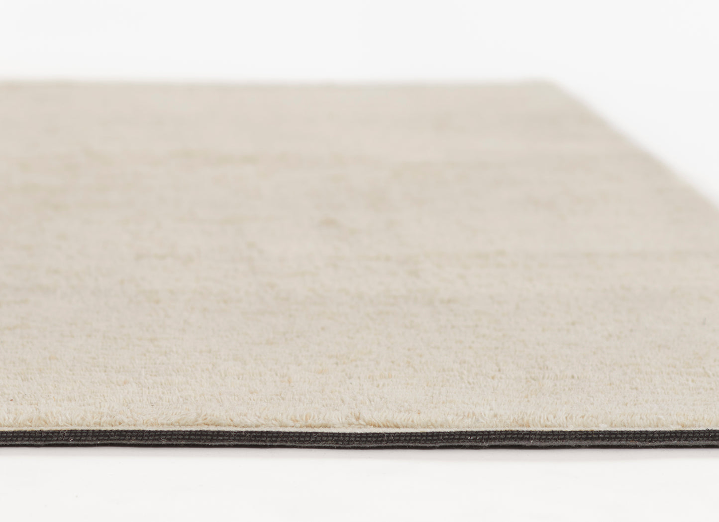 Cream beige rug with dark-edged binding, close-up of soft textured pile and slim black border.