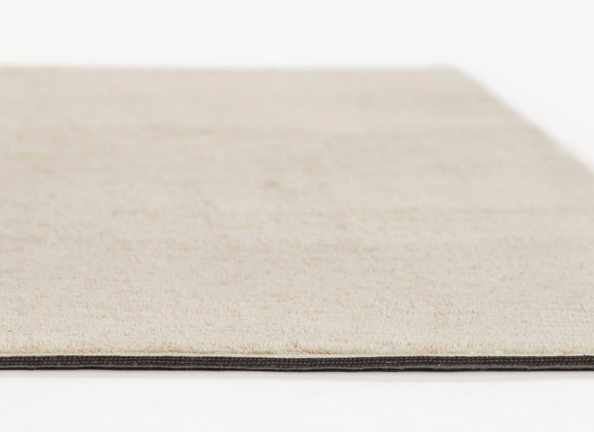 Cream beige rug with dark-edged binding, close-up of soft textured pile and slim black border.