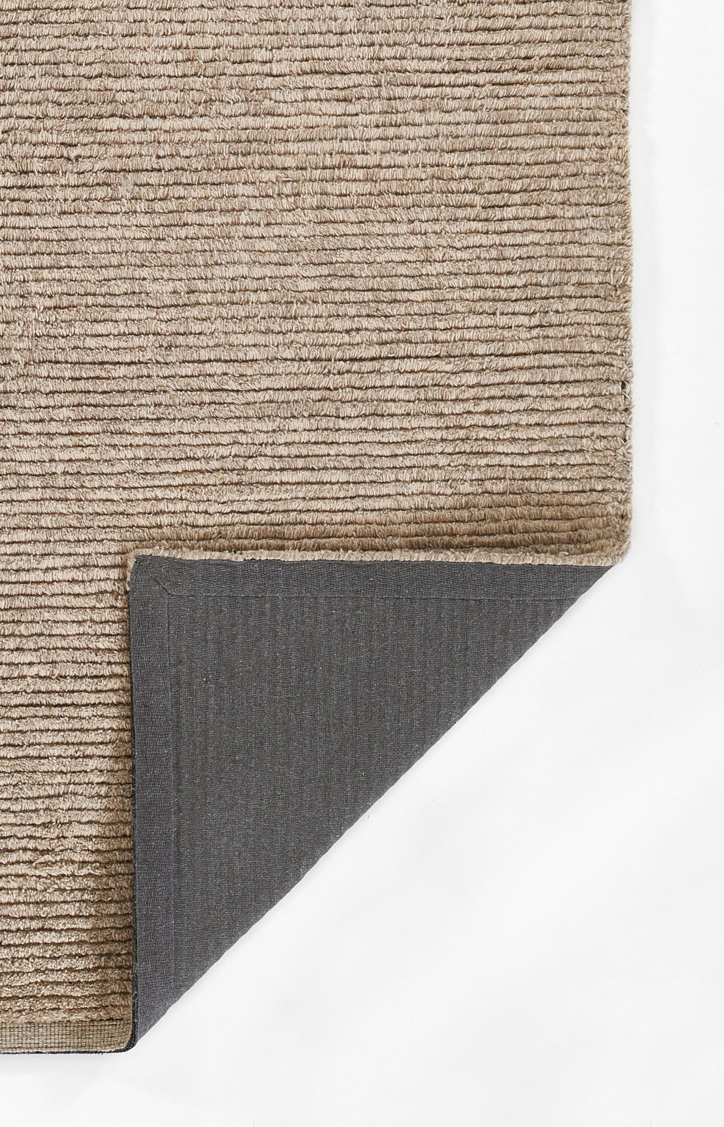 Beige textured loop-pile rug; soft, neutral lounge accent with dark grey underside visible at folded corner.