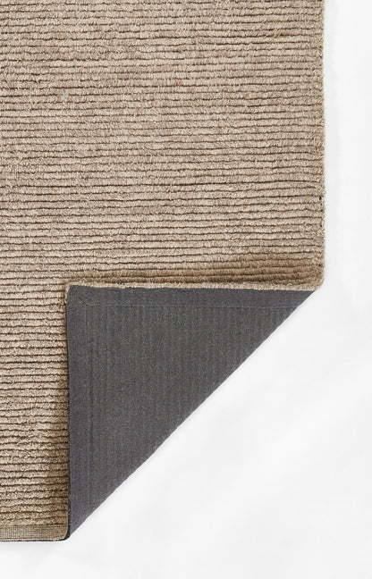Beige textured loop-pile rug; soft, neutral lounge accent with dark grey underside visible at folded corner.