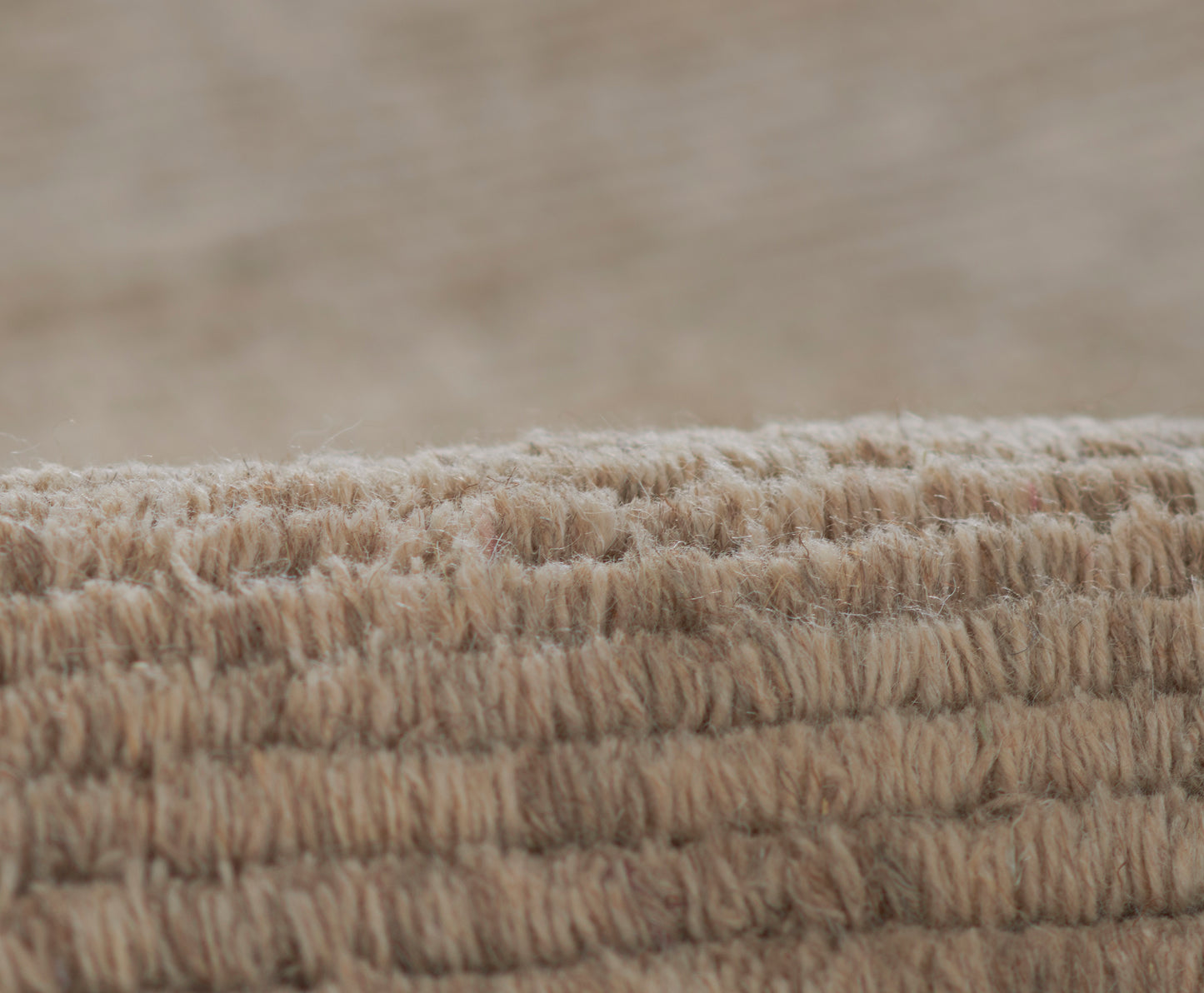 Beige loop-pile rug edge with thick soft fibers; natural woven texture for cozy neutral decor.