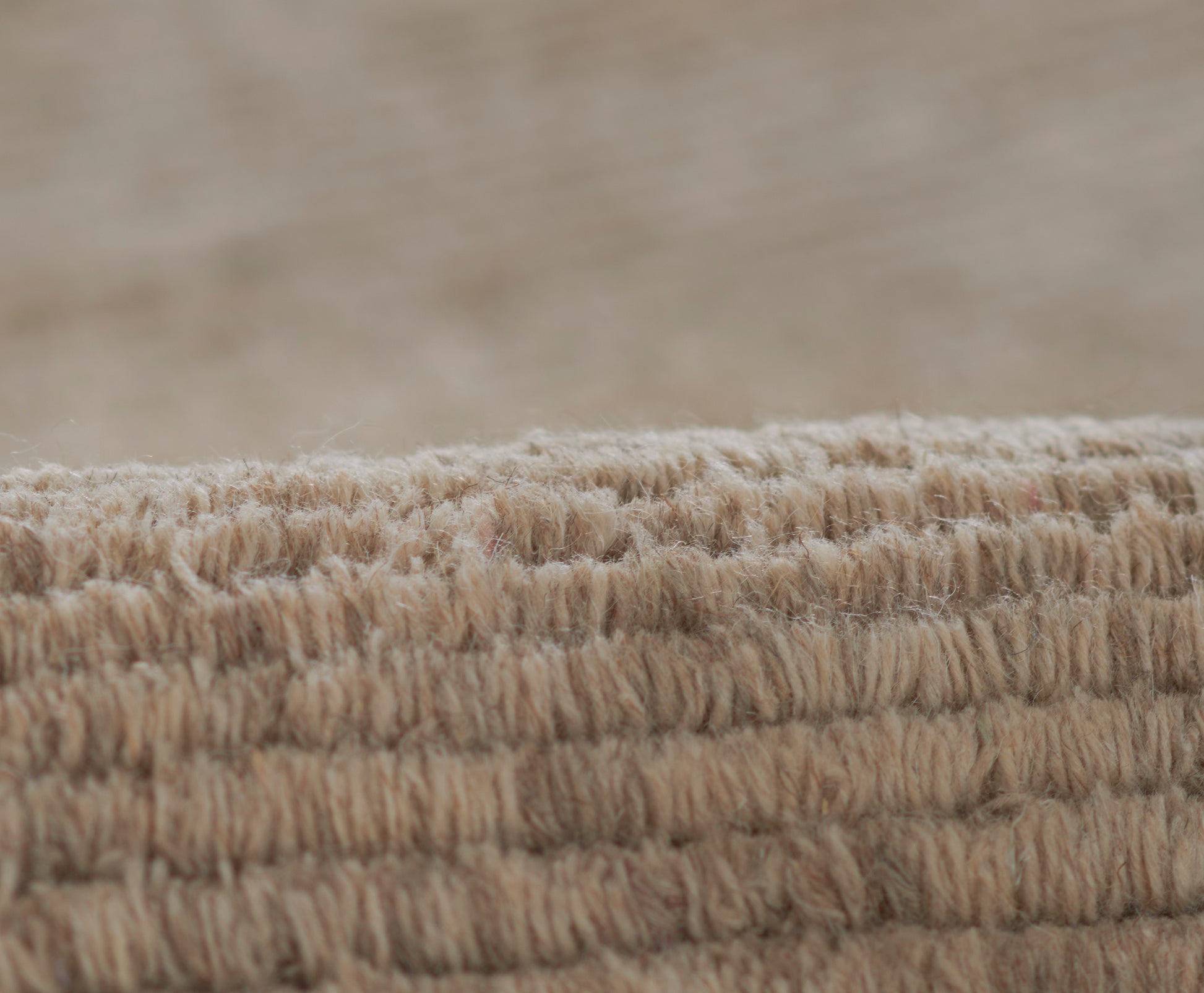 Beige loop-pile rug edge with thick soft fibers; natural woven texture for cozy neutral decor.