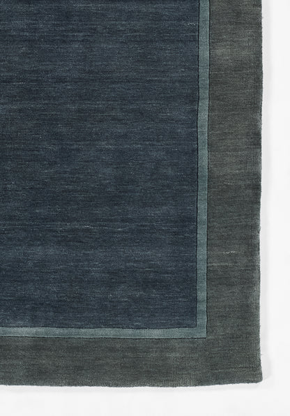 Dark indigo rug with pale teal border trim and outer edge; rectangular, textured woven textile.