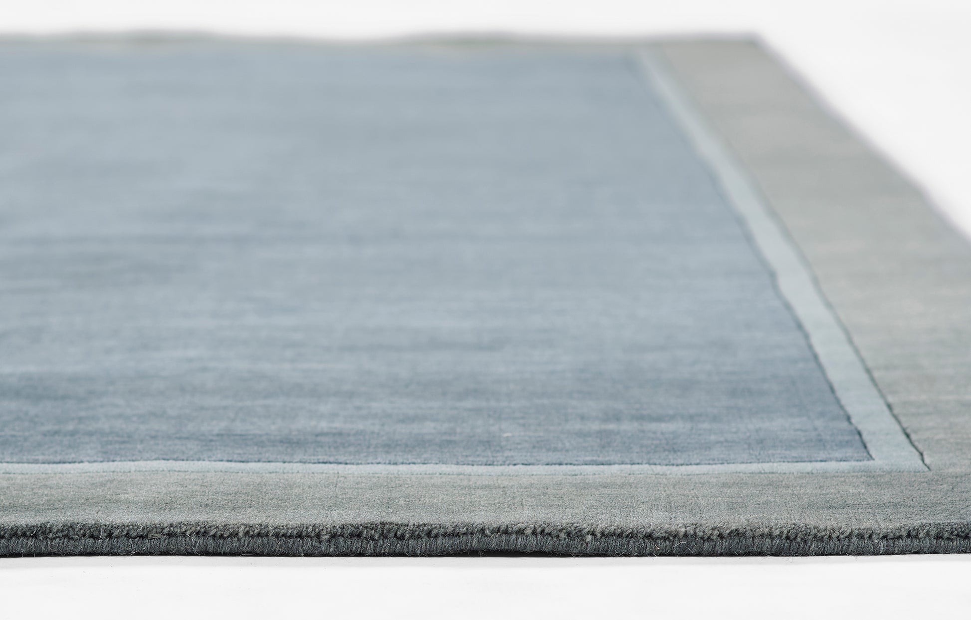 Blue area rug with light gray border and darker outer edge, soft pile, rectangular modern design.