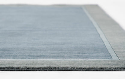 Blue area rug with light gray border and darker outer edge, soft pile, rectangular modern design.