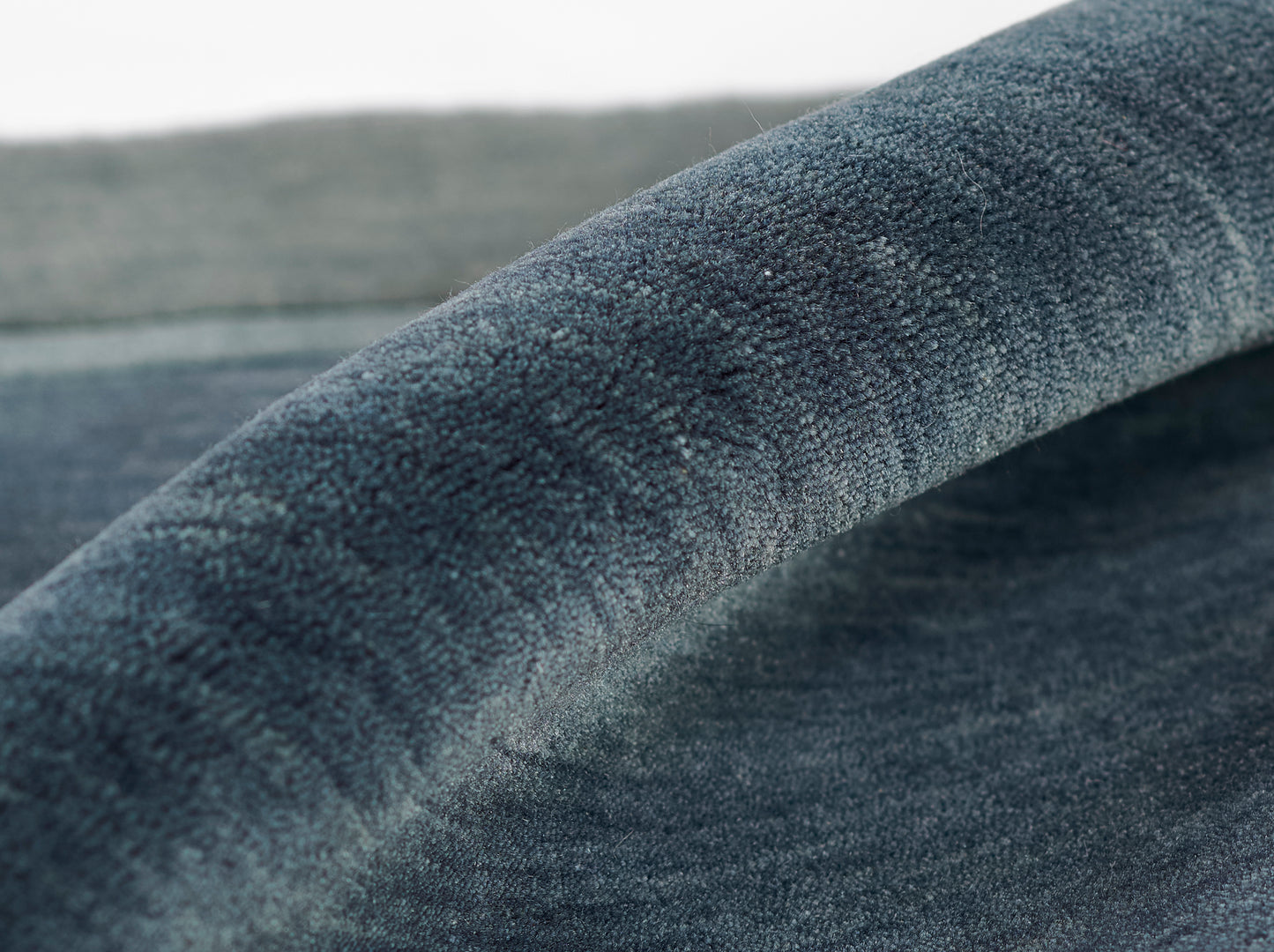 Close-up of deep blue velvet-like fabric with soft nap and curved fold.