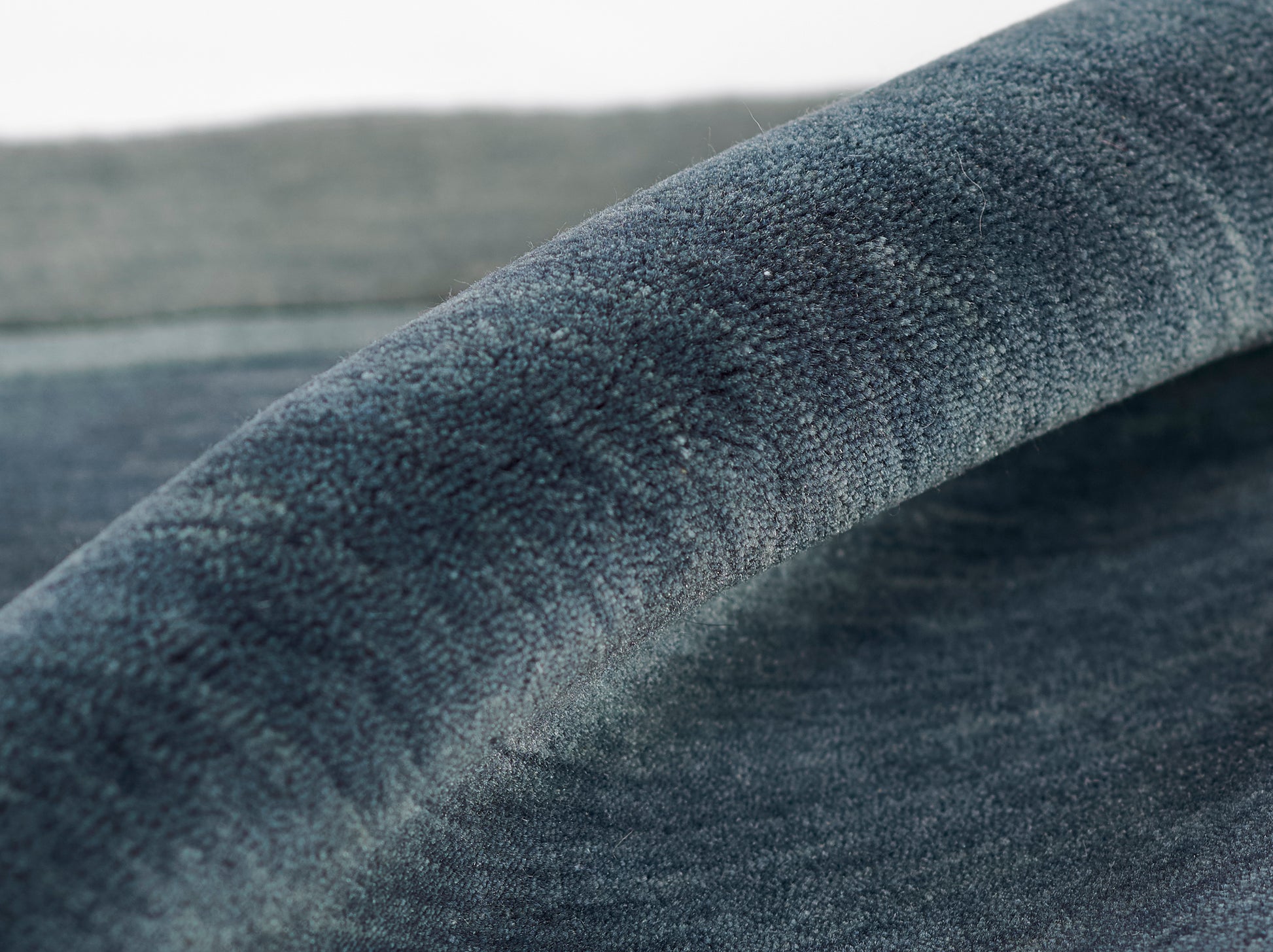 Close-up of deep blue velvet-like fabric with soft nap and curved fold.
