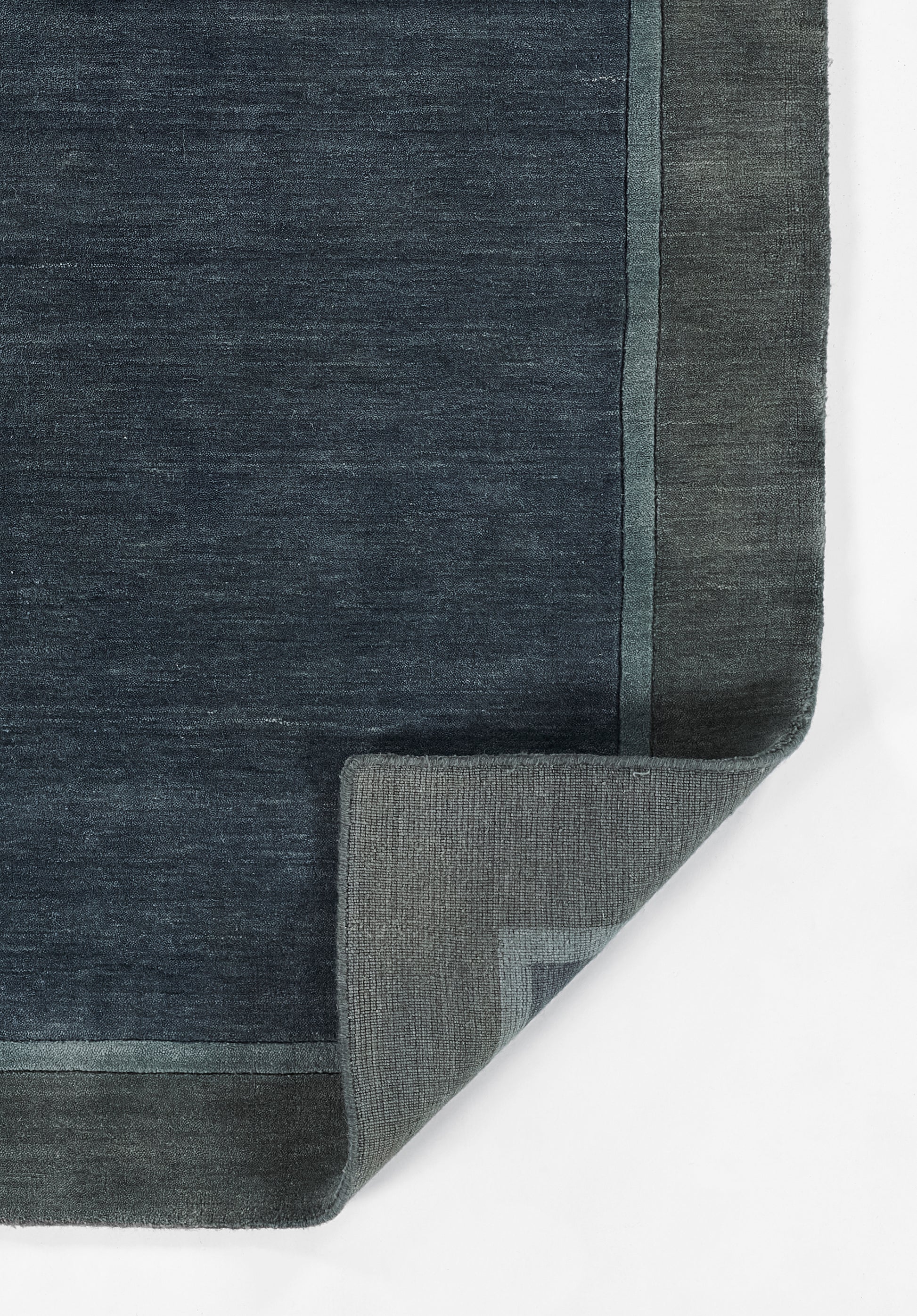 Dark blue rug with pale blue border and folded corner revealing underside.