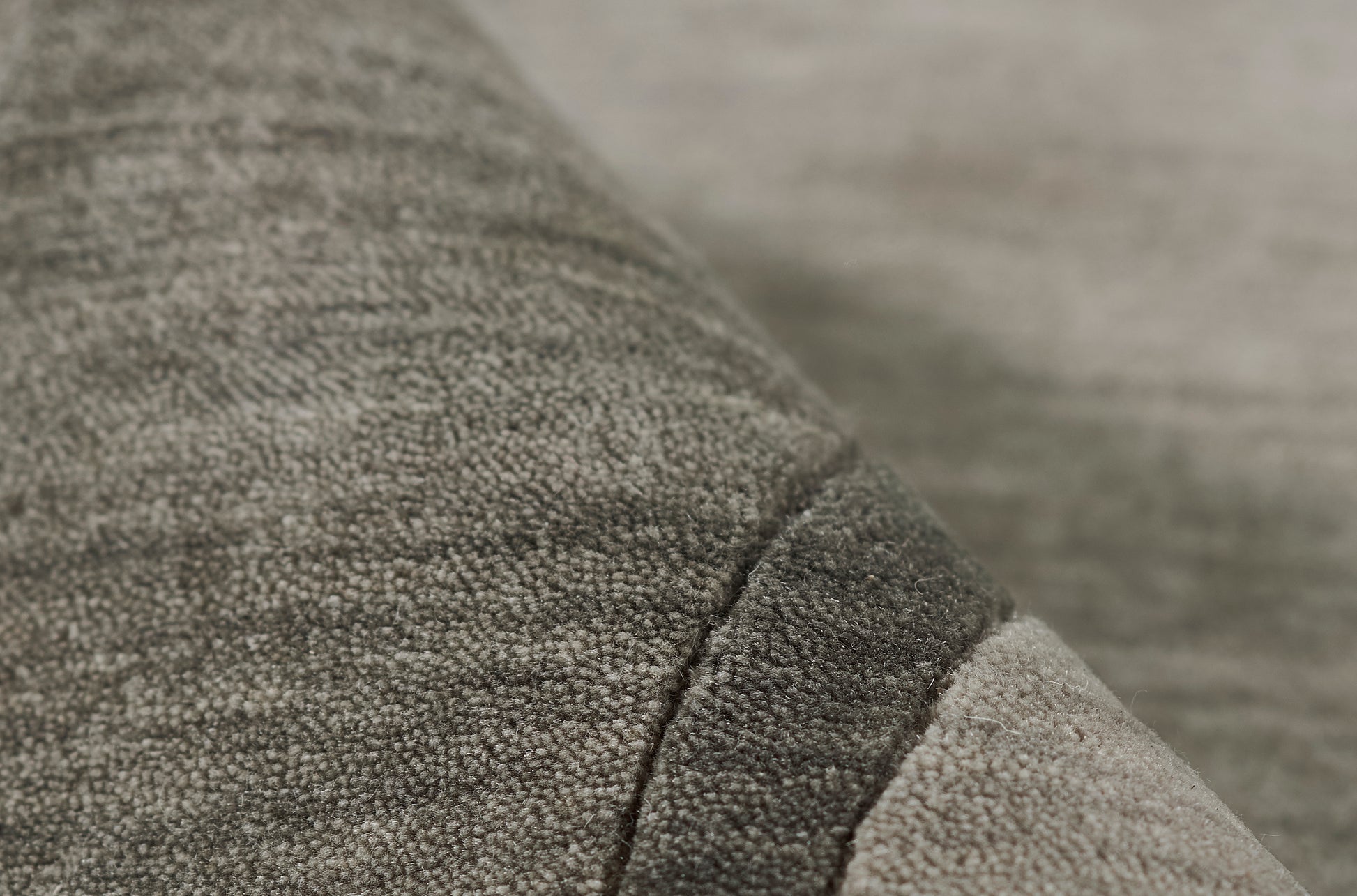 Close-up of gray boucle fabric with a dark seam and lighter edge, plush cozy textile.