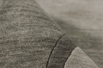 Close-up of gray boucle fabric with a dark seam and lighter edge, plush cozy textile.