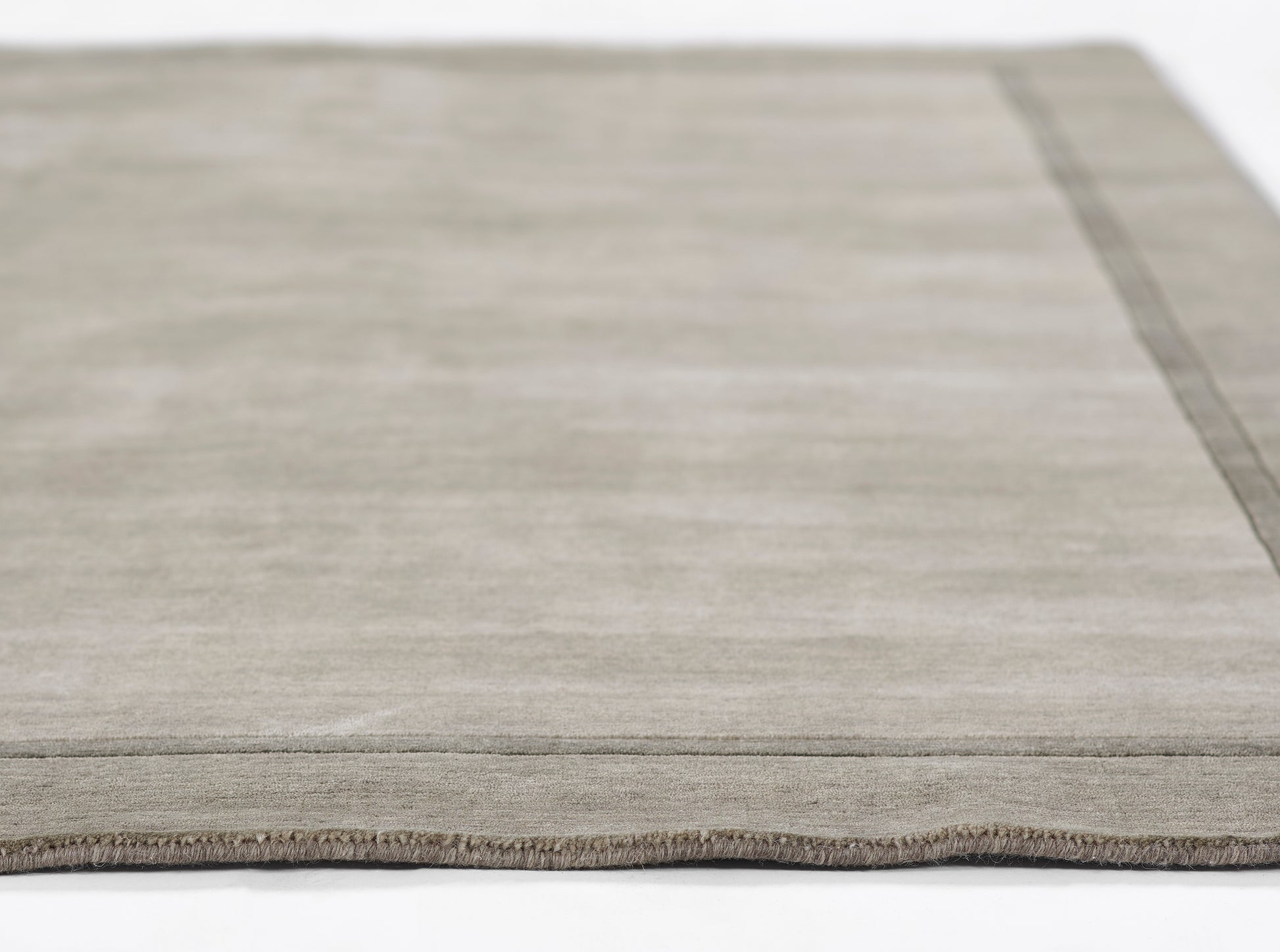 Gray-beige flat-weave rug with a subtle border, low-pile texture, rectangular modern decor.