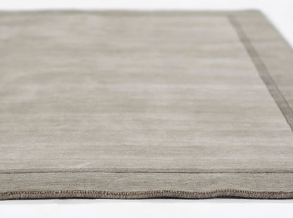 Gray-beige flat-weave rug with a subtle border, low-pile texture, rectangular modern decor.