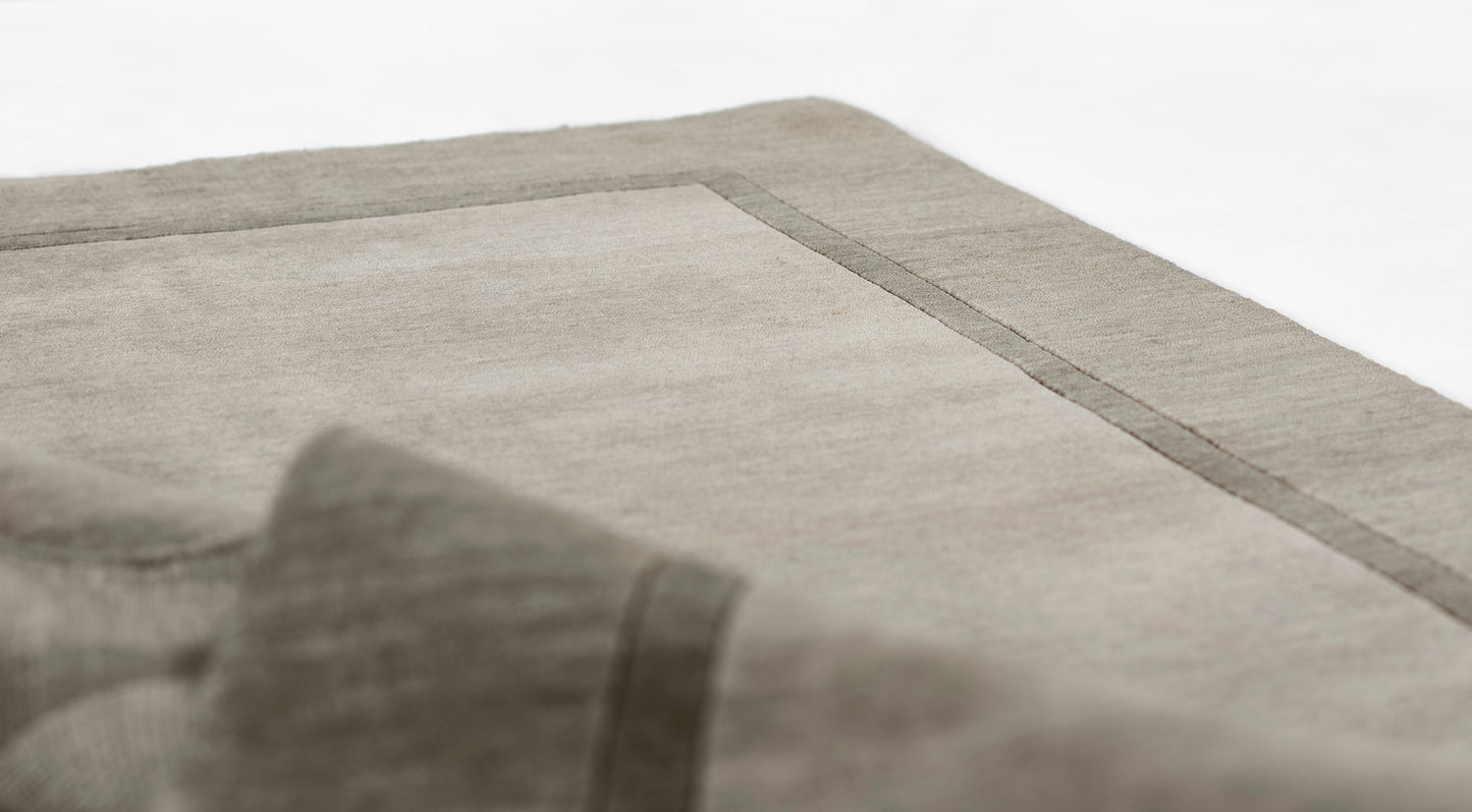 Grey flatweave rug with a darker charcoal border, rectangular, modern minimalist decor for living spaces.