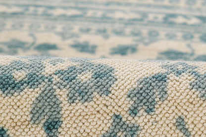 Close-up of a blue and cream woven rug with a soft loop pile and ornate floral pattern.