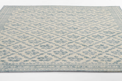 Blue and cream rectangular area rug with repeating floral diamond lattice pattern and decorative border.