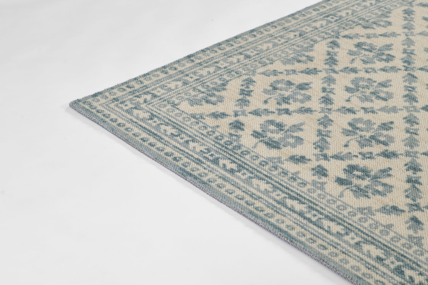 Blue and beige woven area rug with floral motifs and a decorative geometric border.