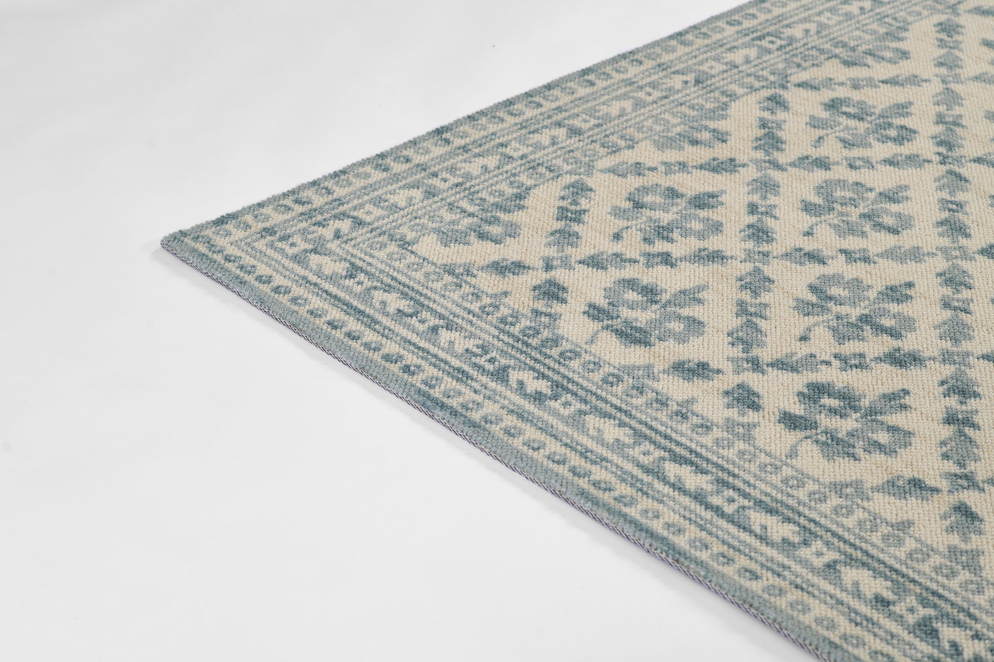 Blue and cream oriental-style woven rug with floral medallion motifs and geometric border.