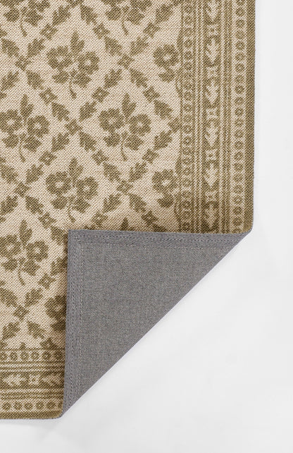 Beige-brown floral patterned rug with ornate border; rectangular shape, folded corner shows blue-gray underside.