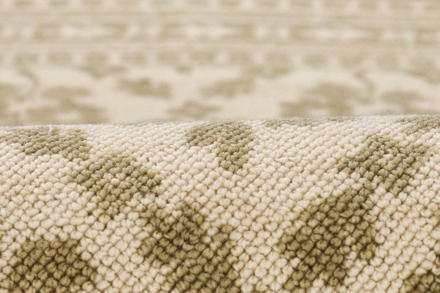 Soft beige and olive-green woven rug close-up, textured pile with geometric pattern.