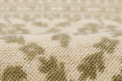 Soft beige and olive-green woven rug close-up, textured pile with geometric pattern.