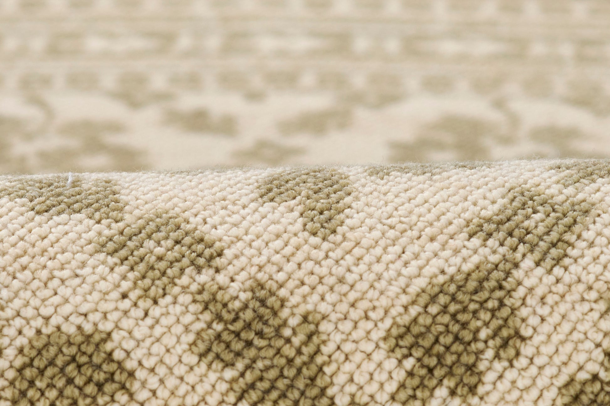 Close-up of beige and olive-green tufted rug with a geometric pattern and soft loop pile.