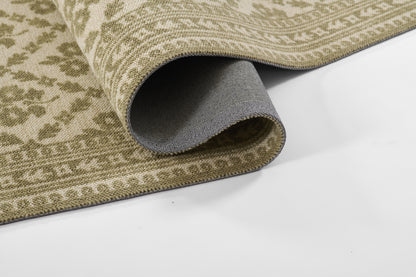 Beige and sage-green patterned area rug, rolled edge reveals gray underside; tight woven texture.
