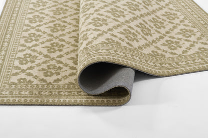 Beige and sage green oriental rug with floral damask pattern and bordered edges, partially rolled to reveal grey backing.