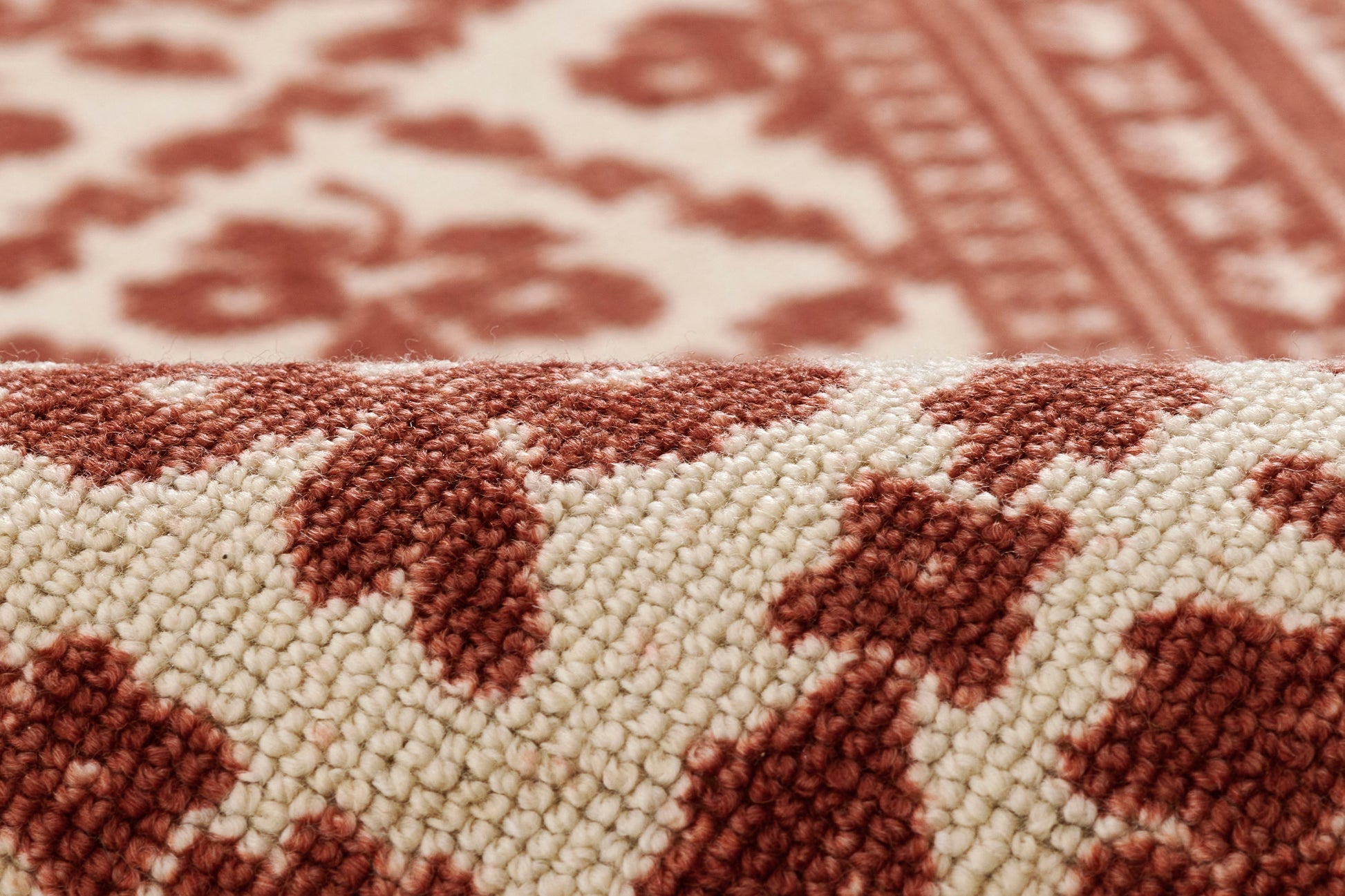 Close-up of a red and cream woven area rug with geometric pattern and plush loop pile.