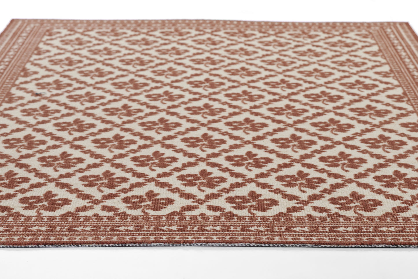 Rectangular rug in red-brown and cream with floral lattice and ornate border; traditional damask-inspired design.