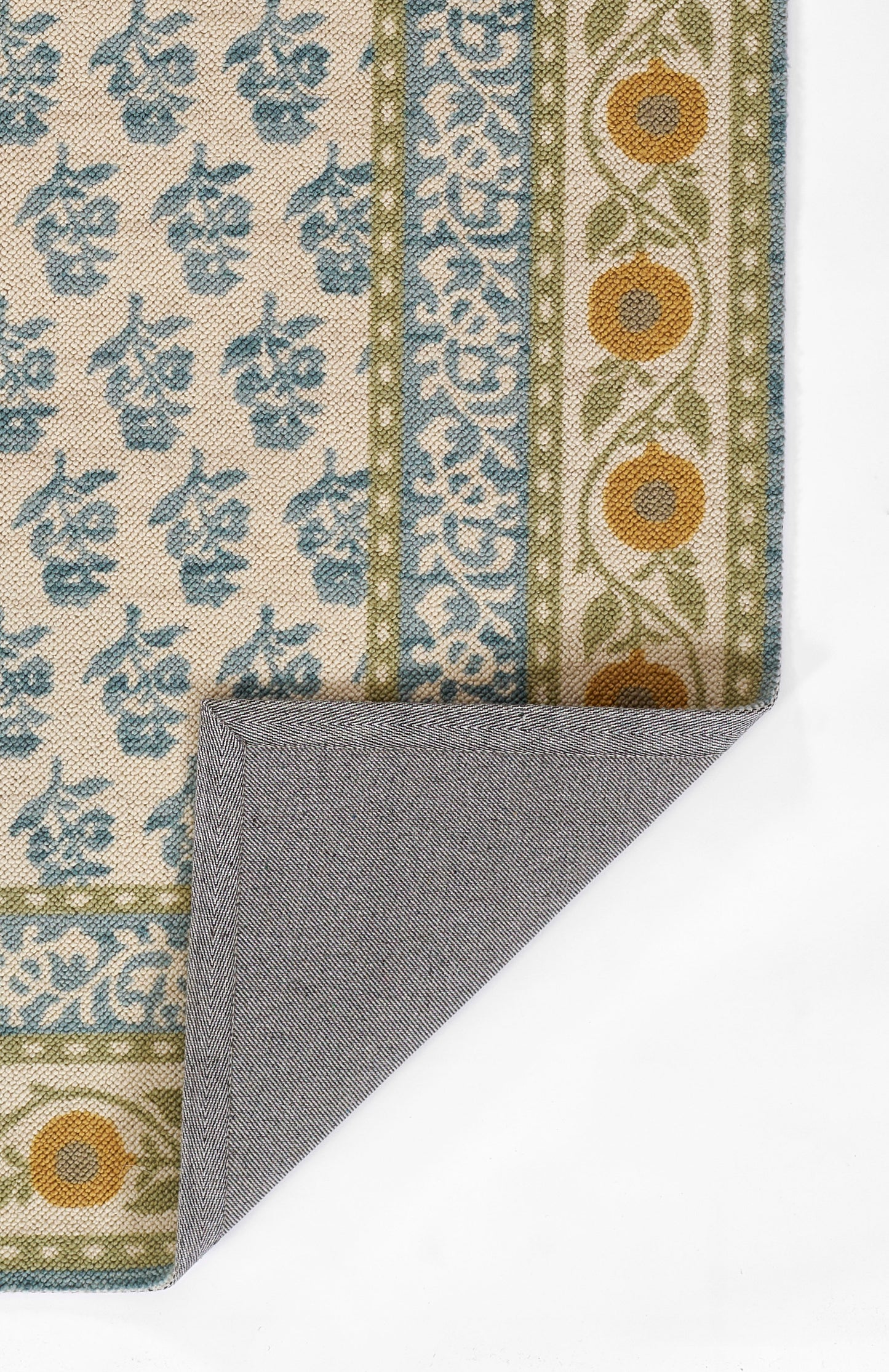 Woven area rug with blue florals on beige field, green borders and orange accents; reversible with gray backing.