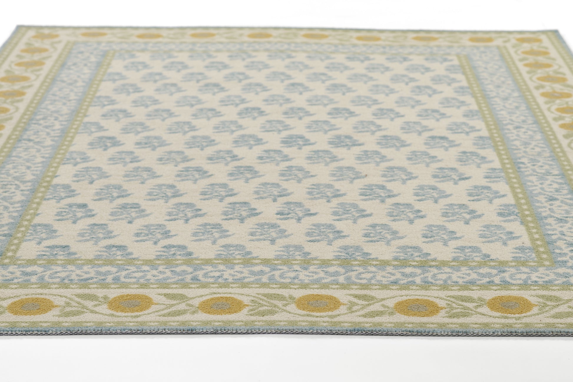 Bibury rug with cream field, pale blue floral lattice, soft green border and yellow sunburst motifs.