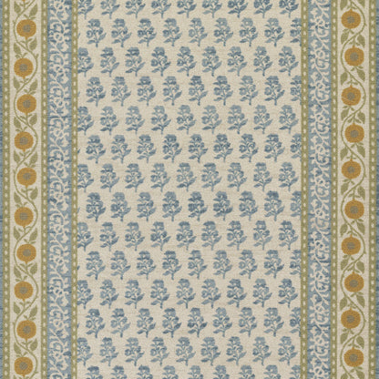 Beige woven rug with blue floral sprigs; bordered by blue patterned borders and olive-green edges with orange circle motifs.
