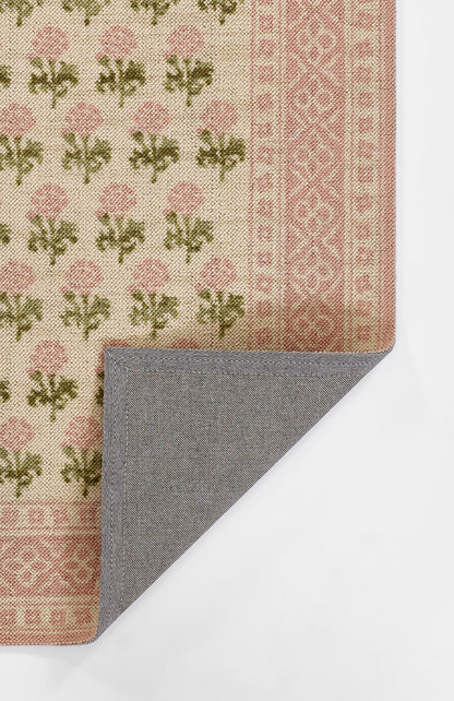 Beige rug with pink floral motifs and border, green leaves; folded corner reveals blue-gray herringbone reverse.
