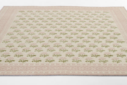 Cream area rug with pink border and repeating green and pink floral motifs; soft, woven textile.