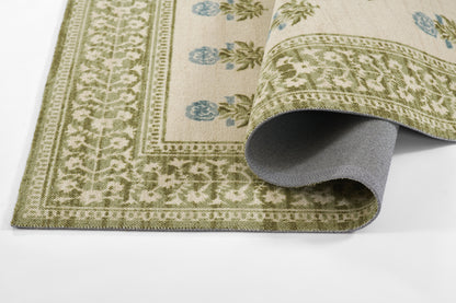 Olive green border rug with cream field and blue floral accents; woven textile, rolled corner shows gray underside.