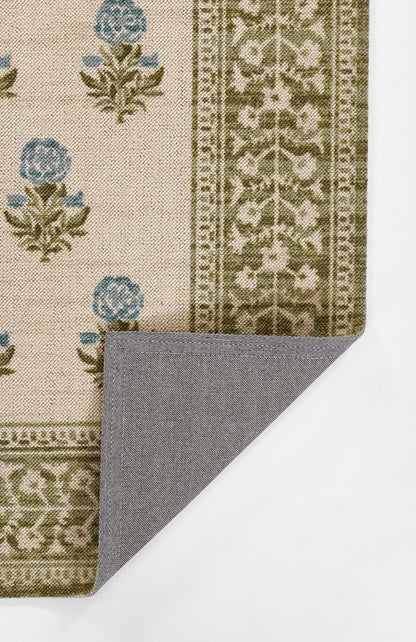 Beige traditional rug with blue floral motifs and olive border; woven texture, corner folded to reveal grey backing.