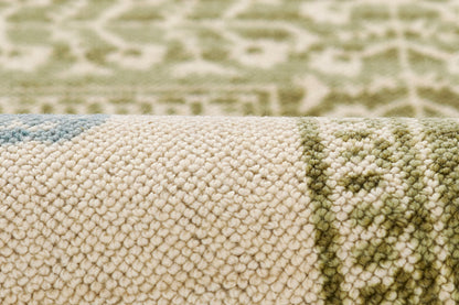Beige loop-pile rug with olive green geometric border and blue accents, close-up texture.