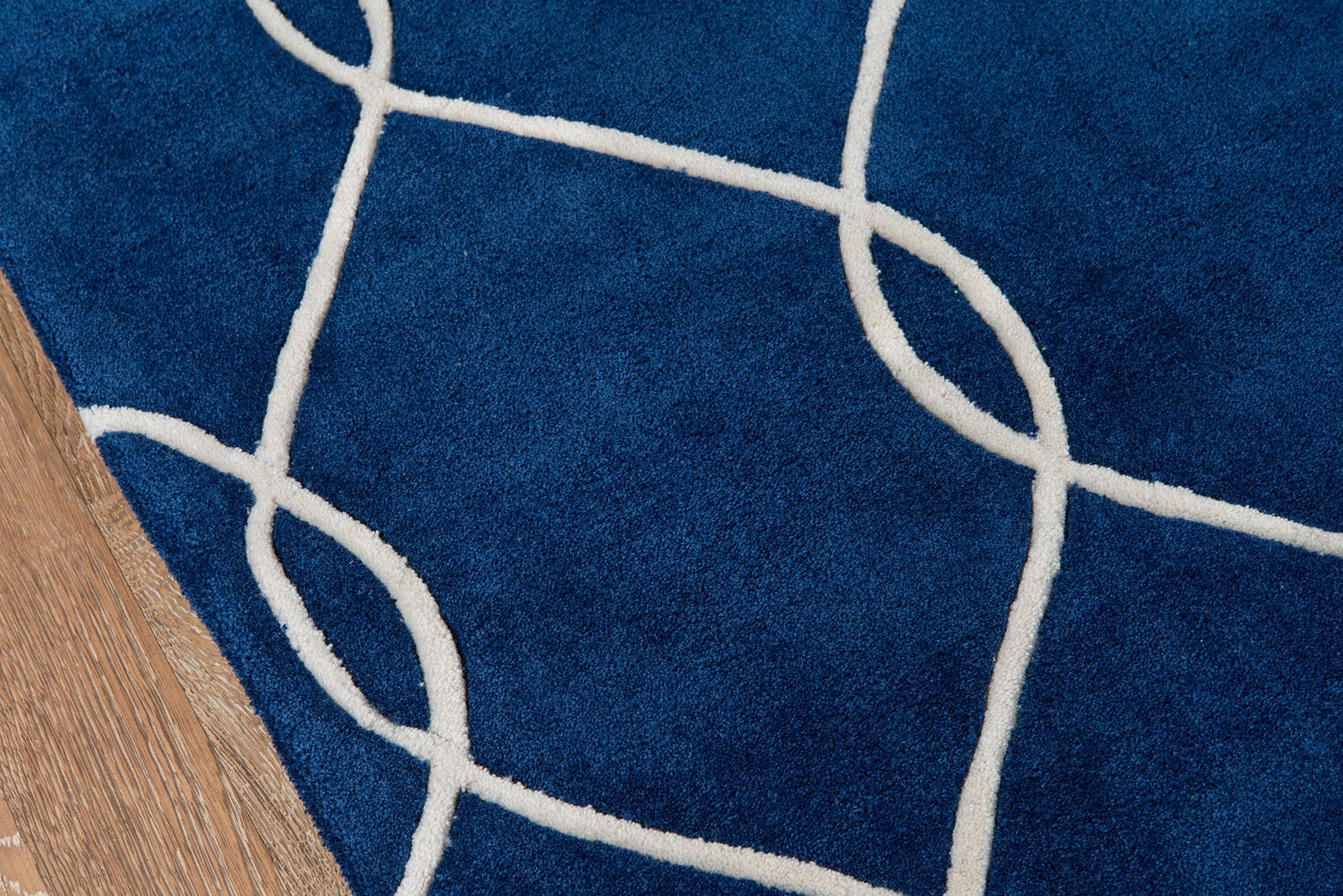 Navy blue area rug with white looping line motif on wood floor.
